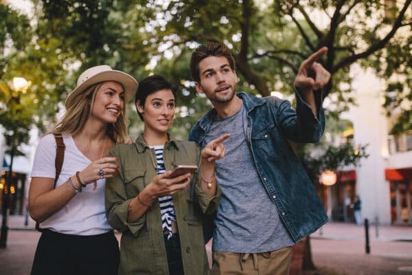 Group of friends on city tour using mobile phone for navigation. Three young people exploring a city using smart phone gps.