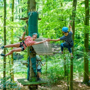 Twee mensen high fiven aan zipline in klimbos Fun Forest