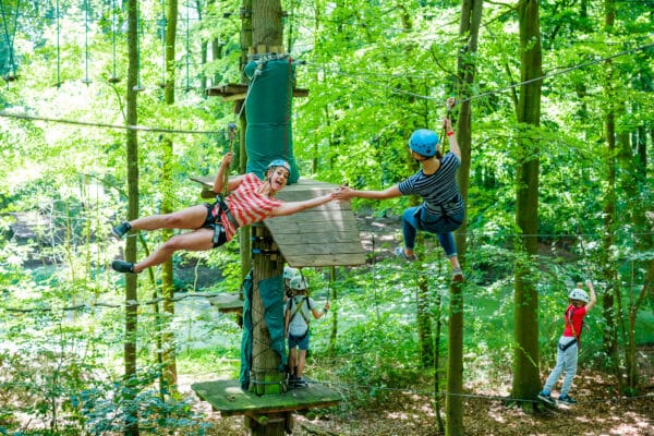 Twee mensen high fiven aan zipline in klimbos Fun Forest